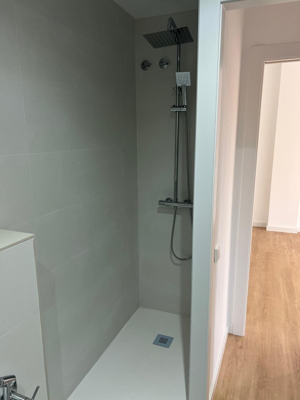 Baño reformado con plato de ducha y revestimiento efecto mármol