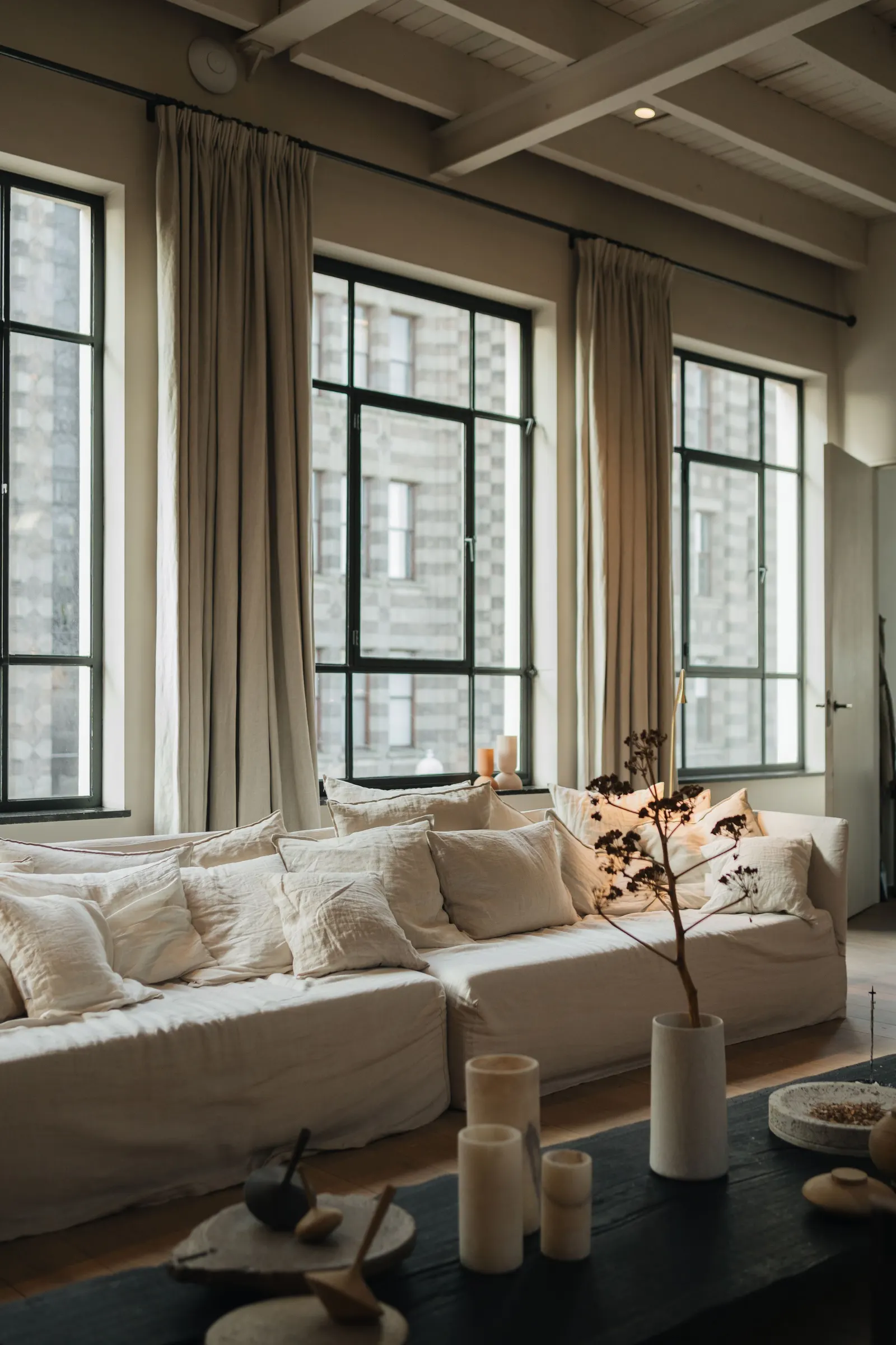 Salón luminoso con sofá de lino, cortinas de lino y grandes ventanales